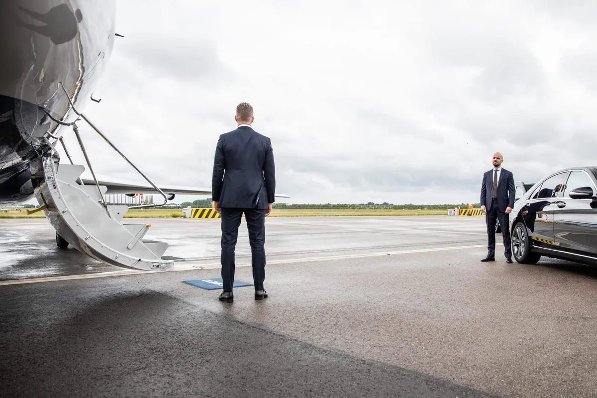 Close protection officers accompanying a client beside a vehicle