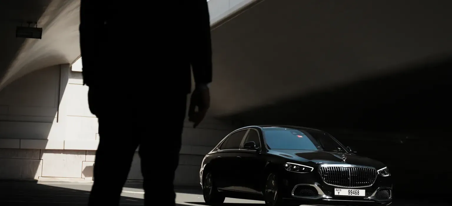 Close protection officers accompanying a client beside a vehicle